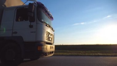 Akşam otoyolda araba araba. Güneş ışığı üzerinde kamyon taksi düşüyor. Arka plan, güzel manzara ile kırsal yoluyla kamyon sürmek. Yan görünümü ağır çekim yakın çekim