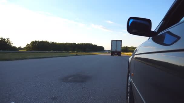 Fekete autó vezetés úton a vidéken. Gyönyörű táj tükröződik a kocsi ajtaján. Forgalom, a vidéki területeken. Szempontból lassú mozgás — Stock videók