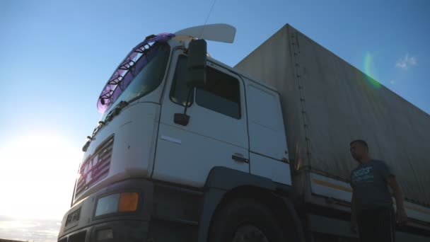 L'autista apre la porta e si siede in un camion parcheggiato. Bellissimo paesaggio sullo sfondo. Il camion si fermò in campagna. Vista dal basso rallentatore Close up — Video Stock