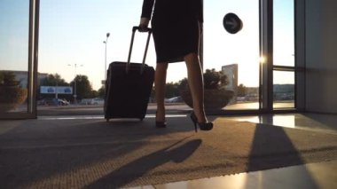 İş eş bavulunu havaalanına. Genç kadın cam kapılardan terminali ve rulo bavul tekerlekleri üzerinde yürüme girerek topuklar. Seyahat veya tatil seyahat kavramı. Ağır çekim