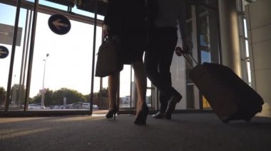 Tekerlek üzerinde cam kapılar ve rulo bavul terminal bırakarak kadın meslektaşı ile iş adamı. İş erkek ve kadın havaalanından şehre kendi bavullarla sokak gidecek. Ağır çekim