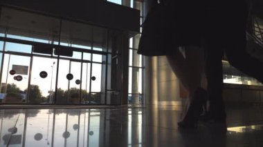 Kadın meslektaşı çıkmak için terminal ve rulo bavul tekerlekleri üzerinde yürüme ile iş adamı. İş adamı ve Havaalanı veya ofis binasında adım kadın. Seyahat kavramı. Ağır çekim