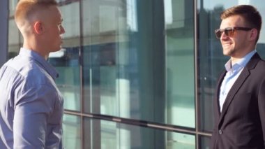 Bina ve tartışmaya ofis duran iki yakışıklı iş adamları iş. Genç meslektaşları konuşmak ve kentsel ortamda el sallayarak. İletişim iş kavramı. Yan görünümü kapatın