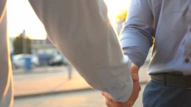 İki genç meslektaşlarının toplantı ve city adlı sokak sunset Bulvarında tokalaşırken Dolly atış. Birbirlerini tebrik otopark arabalar arka planı başarılı iş adamları. İş el sıkışma açık.