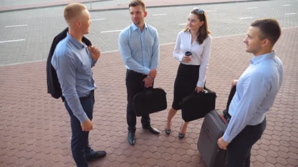 Grupo de jóvenes empresarios felices se encuentra en un círculo y habla después del vuelo. Hombres de negocios sonrientes discuten su viaje de negocios. Concepto de trabajo en equipo y viajes. Cámara lenta Primer plano — Vídeos de Stock