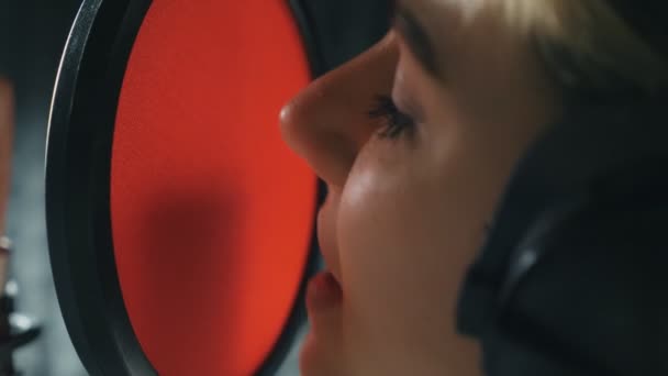 Mouth of female singer singing song in sound studio. Young girl recording new song. Woman in headphones sings to microphone. Working of creative musician. Show business concept. Slow motion Close up — Stock Video