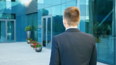 Çalışmaya commuting genç iş adamı. Office giderken takım elbise olmanın kendine güvenen bir adam. Şehir yakındaki modern Binası sokak yürüyüş evrak çantalı iş adamı. Ağır çekim arka geri görüntülemek kapat