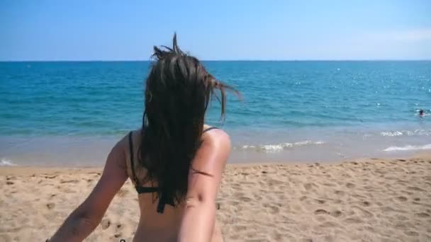 Kövess egy fiatal nőt, amint kihúzza a barátját a tengerpartra. Gyönyörű lány fogja férfi kezét, és fut üdülőhely strand az óceán. Nyaralás vagy nyaralás. Álláspont POV Lassított mozgás — Stock videók