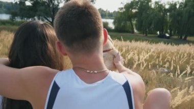 Genç çift, çayır çim üzerinde oturan ve onun labrador okşayarak. Aile ile birlikte hayvanını doğada vakit geçiriyor. Çift ile onların Evcil hayvan tadını çıkarın. Arka arkadan görünüm yavaş hareket yakın çekim