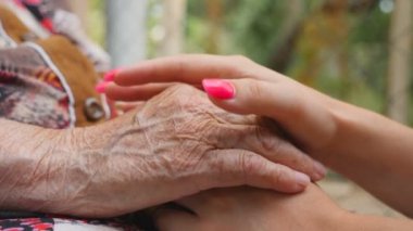 Güzel manikürlü genç kadın kolları yaşlı bir kadını rahatlatıyor. Torunumla büyükannem dışarıda vakit geçiriyorlar. Şefkatli ve sevgi dolu bir kavram. Yavaşça kapat.