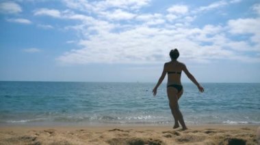 Yükseltilmiş eller ve okyanus plaj üzerinde çalışan tanınmaz halde genç bir kadın. Kumlu sahilde denize koşu ve tatil sırasında özgürlük zevk güzel kız. Yaz tatile dinlenmek. Ağır çekim