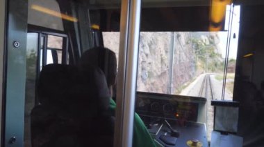 Tanınmayan tren sürücüsü dağ yolunda elektrikli tren kullanıyor. Şoför kabininden demiryolu hattına kadar. Arka plan POV Yavaş çekim Yakın çekim