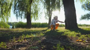 Genç baba ve küçük çocuğunu bulmak ağacının gövde delik gün güneşli yaz iç içe. Mutlu bir aile birlikte doğa zaman harcama. Arka plan, güneş ışığı. Düşük açılı görünüş ağır çekim