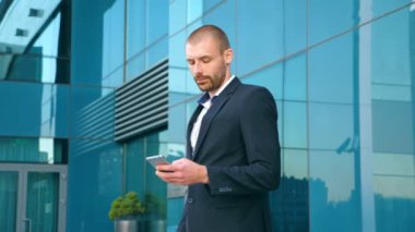 Akıllı telefon kullanma office ve başarı kutluyor genç iş adamı. İş adamı smartphone ve olumlu duygular sahip iyi haberleri okuyun. Adam portresi başarı ile mutlu. Ağır çekim