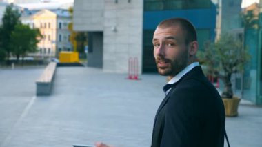 Yakışıklı işadamı ofis ve kameraya bakarak yakınındaki telefonda konuşuyor. Cep telefonu yanında modern bina açık konuşan genç iş adamı. Dışında konuşmayı adam portresi. Yakın çekim.