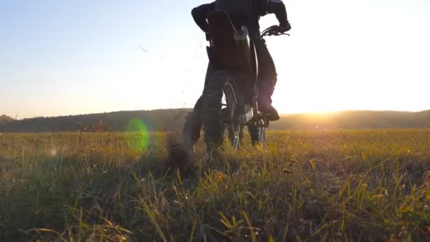 Ruota di moto motocross che inizia a girare e scalciare terra o sporcizia. Moto che inizia il movimento. Motociclista cavalca all'ora del tramonto. Bellissimo paesaggio sullo sfondo. Rallentatore Close up — Video Stock