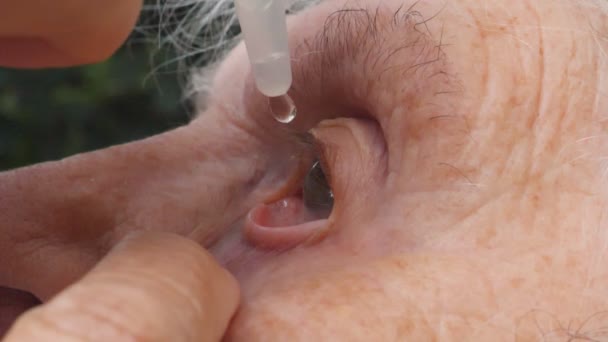 Profile of old woman dripping medical drops in her eye. Portrait of grandmother with infection and inflammation of eyes. Concept of healthcare and medicine. Side view Close up Slow motion — Stock Video