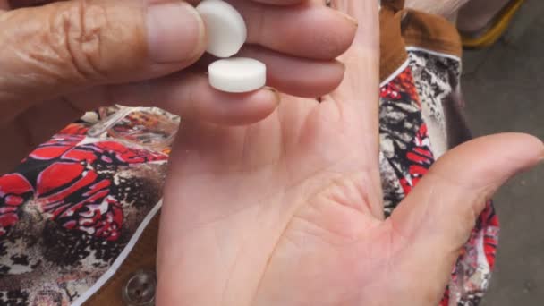 Vista superior de la abuela lanzó tabletas de una mano a la otra. Una anciana poniéndose dos pastillas blancas en el brazo. Concepto de salud y medicina. Primer plano: cámara lenta — Vídeos de Stock