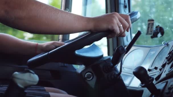 Unrecognizable man holding his hands on steering wheel and driving car at country road on warm summer day. Truck driver rides to destination. View from the lorry cab. Slow motion Close up Video Clip