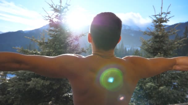 Un atlético irreconocible parado en el balcón y levantando las manos en un día soleado. Joven disfrutando de vacaciones o vacaciones. Montaña y bosque al fondo. Vista posterior trasera Cerrar Cámara lenta — Vídeos de Stock