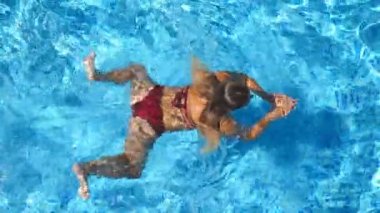 Kırmızı bikini Otel havuz rast yüzer tanınmaz halde güzel kız. Genç kadın güneşli günde Havzası masmavi suda yüzmek. Yaz tatili veya tatil kavramı. Üstten görünüm kapat