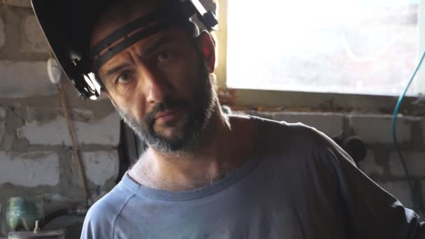 Mecânico sorrindo e olhando para a câmera. Retrato de homem feliz com barba trabalhando em sua garagem ou oficina. Feche emoções do funcionário masculino com a expressão contente no rosto. Movimento lento — Vídeo de Stock