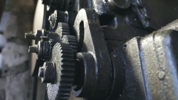 Close up of rotation gear system. Bottom view on dirty spinning cogwheels of metal workbench working in garage. Blurred background. Slow motion Close up — Stock Video