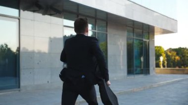 Evrak çantası ile tanınmaz işadamı şehir sokak çalışır. Toplantı için geç iş adamı. Yakındaki modern Binası takım elbise koşu başarılı adam. Randevu için acele adam. Arkadan görünüm ağır çekim