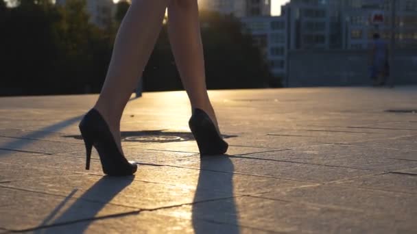 Sledujte na ženské nohy v vysoké podpatky obuvi chodit po ulici v západu slunce. Nohy z obchodních žena v obuvi s vysokými podpatky v městě. Dívka, krokování do práce. Pomalé mo zblízka boční pohled — Stock video