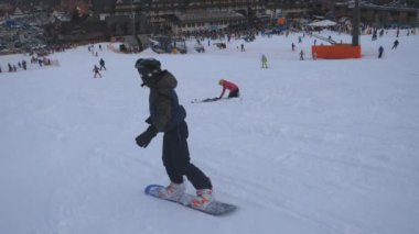 Kış tatil taze kar üzerinde azalan Snowboard düşkünleri. Tanınmayan erkek dağ karlı yamaç aşağı kayan. Hill ve zevk tatil binmek için öğrenme insanlar. Arka geri görüntülemek ağır çekim