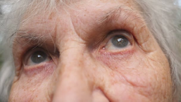 Retrato de la vieja abuela mirando hacia arriba. Cerrar los ojos de una anciana con arrugas a su alrededor — Vídeos de Stock