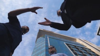 Üç Genç İşadamları toplantı ve diğer Ofis Binası yakınındaki selamlıyorum. Arka plan mavi gökyüzüne elini sıkarken erkek arkadaşları. Karşılıklı iş ortakları açık. Düşük açılı görünüş ağır çekim