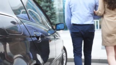 Kendine güvenen işadamı ve araba çıktı ve kentsel sokakta yürüyen güzel bir işkadını. İş çift otomatik ve işe yarayacak dışarı geldi. Bulanık hareket. Ağır çekim arkadan görünüş