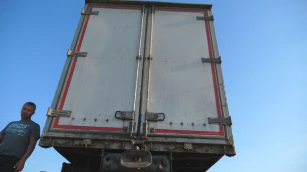 Driver comes to parked truck and opens door of trailer at summer sunny day. Lorry stopped in the countryside. Bottom view Slow motion Close up — Stock Video