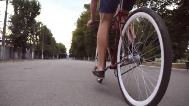 Park yolunda antika bir bisiklet süren genç bir adam. Sportif adam dışarıda bisiklet sürüyor. Sağlıklı aktif yaşam tarzı. Düşük açı. Ağır çekim.