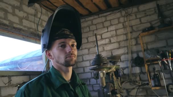 Moe mechanic camera kijken. Man in werkkleding werken in zijn garage of atelier. Slow motion close-up zijaanzicht — Stockvideo