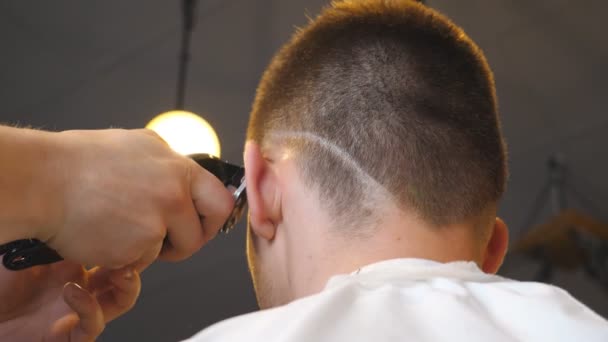 Brazos de peluquero haciendo corte de pelo masculino al cliente con clipper en el salón. Manos de peluquero cortando el pelo de su cliente con maquinilla de afeitar eléctrica en la barbería. Proceso de peinado. Vista trasera Primer plano — Vídeo de stock