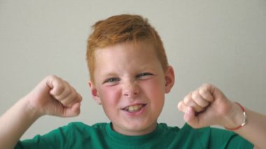 Kameraya bakarak ve yetiştirme sevimli yakışıklı çocuk mutluluk başarı kapalı eller. Pozitif ile genç çocuk mutlu ve sevinç duygular onun yüzünde. Çilli çocuk portresi. Yavaş mo yakın çekim