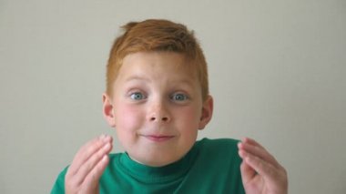 Genç çocuğun kafasını yüzünde sevinç ve zevk gösterilen debriyaj yapar. Çok güzel çocuk ile duygu ve duygu yüzünü kameraya benziyor. Çilli kapalı mutlu çocuk portresi. Ağır çekim yakın çekim