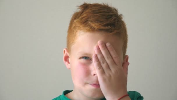Porträtt av seriös rödhårig pojke med fräknar. Desperat unge tänker på sina problem inomhus. Närbild känslor manliga barn med sorgliga uttryck i ansiktet. Långsamma rörelser — Stockvideo