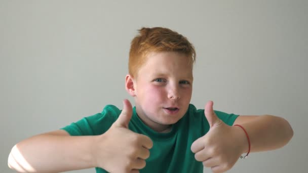 Adorable bébé se réjouissant de la réalisation et montrant pouces vers le haut. Gros plan sur les émotions de l'enfant mâle avec expression de joie sur le visage. Portrait de beau garçon aux cheveux roux heureux avec des taches de rousseur à l'intérieur. Mouvement lent — Video