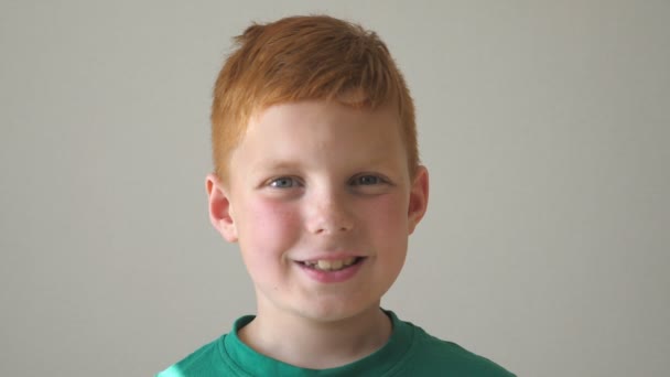 Portrait de garçon aux cheveux roux heureux avec des taches de rousseur. Adorable bébé regardant dans la caméra avec des yeux larges et riant à l'intérieur. Gros plan sur les émotions d'un bel enfant mâle avec une expression heureuse sur le visage. Mouvement lent — Video