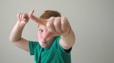 Kameraya dönük ve aralarında en sevindirici bebek. Çiller kapalı olan yakışıklı mutlu Kızıl saçlı çocuk portresi. Yüzünde sevinç ifadesi ile erkek çocuk duyguların kapatın. Ağır çekim