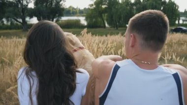 Genç çift, çayır çim üzerinde oturan ve onun labrador okşayarak. Aile onun evde beslenen hayvan vasıl doğa ile birlikte vakit geçiriyor. Adam ve kadının kendi evcil hayvan beraber. Ağır çekim yakın çekim