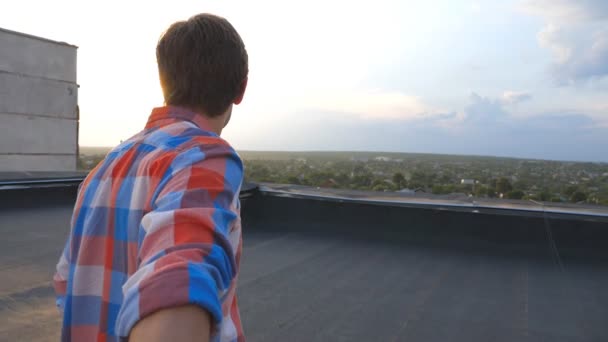 Mann hält Hand seines Freundes und rennt zum Dachrand, um die Aussicht zu bewundern. folgen Sie mir Schuss junger Mann zieht seine Geliebte auf dem Dach. schöne Landschaft im Hintergrund. Zeitlupe — Stockvideo