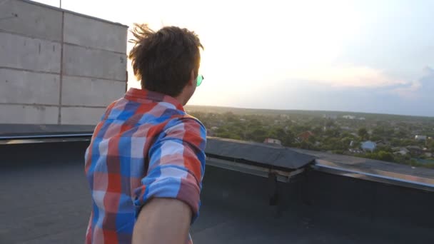 Killen håller handen av sin pojkvän och går till kanten av taket för att beundra utsikten. Följ mig sköt av ung man dra sin älskare på taket. Vackert landskap i bakgrunden. Synvinkel Slowmotion — Stockvideo