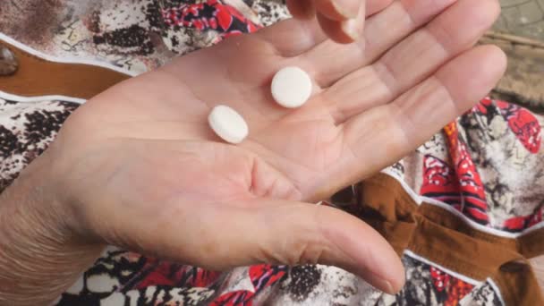 Eine ältere Frau legt zwei weiße Tabletten in ihren Arm. Großmutter warf Tabletten von einer Hand in die andere und drückte sie zusammen. Gesundheitswesen und Medizin. Ansicht von oben Nahaufnahme Zeitlupe — Stockvideo