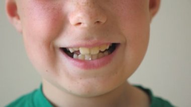 Kapalı alanda gülümseyen ve gülen küçük çocuk ağzını kapat. Yüzünde mutlu bir ifade olan yakışıklı bir çocuğun portresi. İçinde mutluluk gösteren çilli mutlu bir çocuk. Yavaş çekim