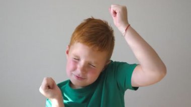 Elleri kapalı yetiştirme ile dans yakışıklı güzel bir çocuk. Onun kapanış mutlu erkek çocuk gözleri ve mutluluk başarı için keyfini çıkarın. İçeride eğleniyor çilli kızıl saçlı çocuk portresi. Ağır çekim