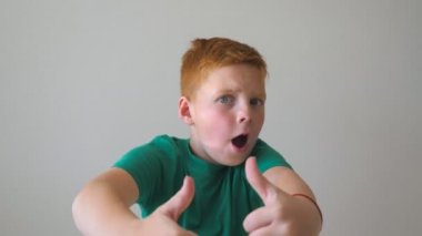Başarı seviniyor ve bir Yaşasın vererek mutlu çocuk kapatın. Erkek çocuk fotoğraf makinesi ve gülümseme işaret parmağı ile işaret. Kapalı çilli kızıl saçlı yakışıklı çocuk portresi. Ağır çekim